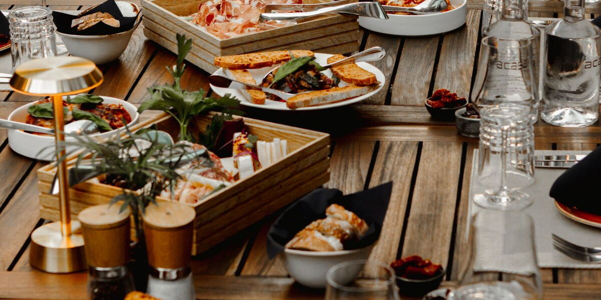 Tavolata - Gartenterrassentisch gedeckt und verschiedene Platten mit authentisch italienischen Gerichten