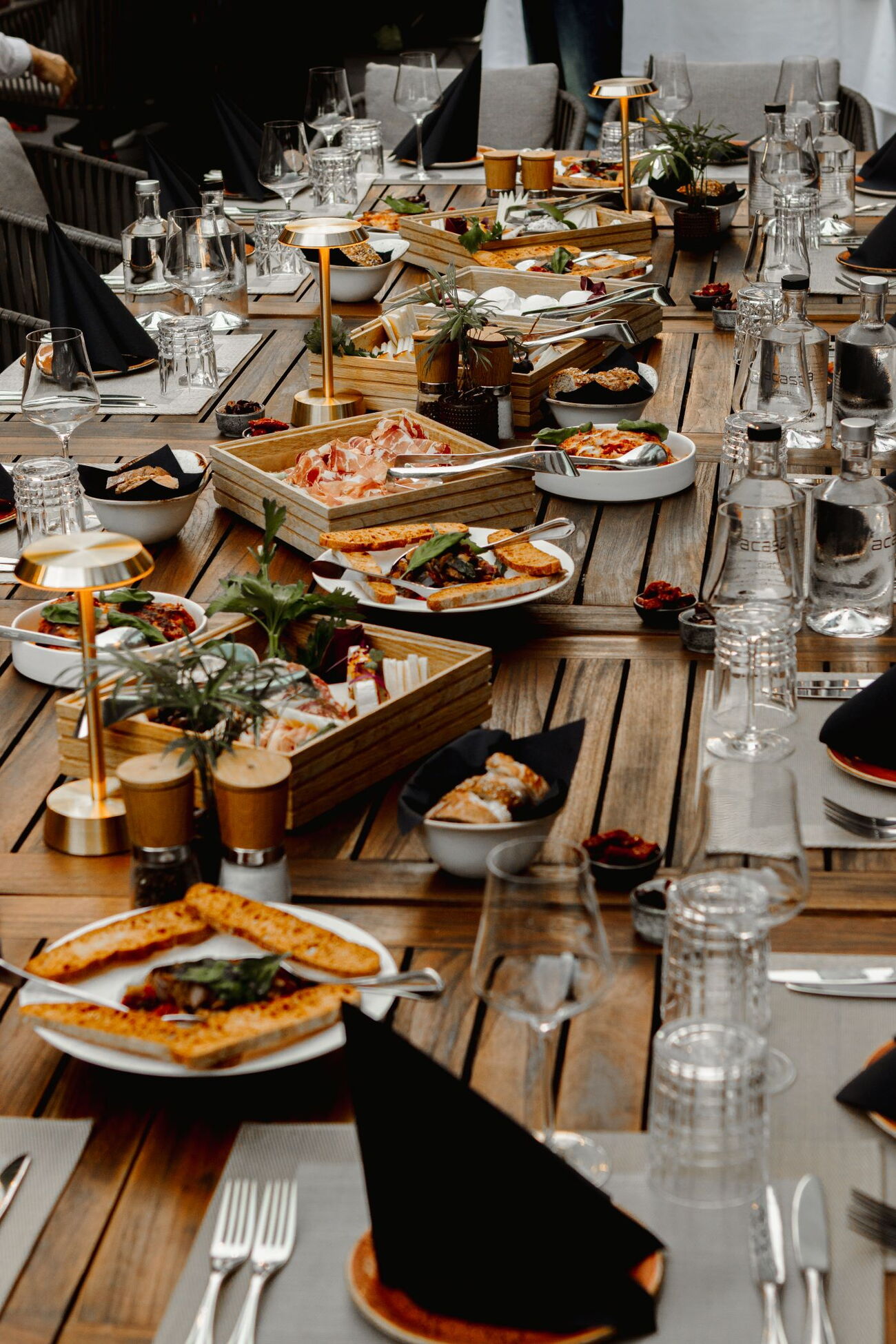 Tavolata - Gartenterrassentisch gedeckt und verschiedene Platten mit authentisch italienischen Gerichten